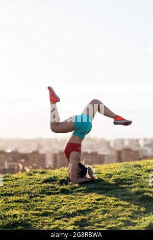 Donna non riconosciuta che indossa abiti sportivi facendo posa yoga e allenarsi nel parco. È forte e flessibile. Foto Stock