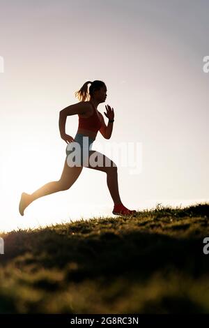 Donna attiva inriconosciuta con abiti sportivi che corrono nel parco e allenarsi la sera. Foto Stock