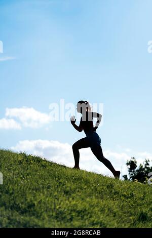 Donna attiva non riconosciuta con abiti sportivi che corrono nel parco e allenarsi. Foto Stock