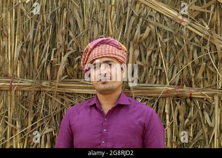 preoccupatevi di meno, agricoltore indiano in piedi piegato a mano nel suo campo di grano sano e sboccando Foto Stock