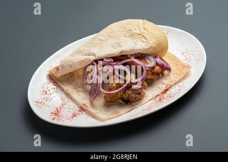 shashlik o carne alla griglia con cipolla in pita su piatto bianco su fondo grigio Foto Stock