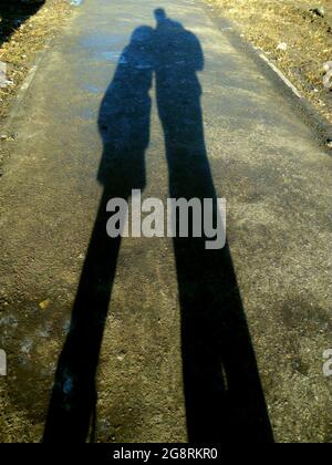 Famiglia felice: Un padre allegro e il suo scolaro, al mattino presto stanno andando sulla strada soleggiata per andare a scuola. Celebrazione del giorno del Padre del mondo Foto Stock