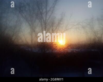 Mattina presto gelata di primavera attraverso la finestra gelida. Tramonto attraverso la finestra. Il concetto di protezione ambientale. Foto Stock