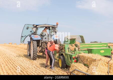 Riverstick, Cork, Irlanda. 22 luglio 2021. Carmel e il trasportatore Amanda apportano le regolazioni a un'imballatrice John Deere 459 nella loro azienda agricola di famiglia. In tutto, imballeranno oltre 3,000 balle quadrate prima di passare a rotonde nella loro azienda di Rivstick, Co. Cork, Irlanda. - immagine; credito: David Creedon/Alamy Live News Foto Stock