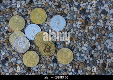 molte monete d'oro e d'argento etere di bitcoin e ada da criptovaluta che giace su una lastra di pietra colorata Foto Stock