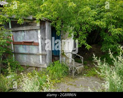 Vecchia poltrona nei pressi di una casetta abbandonata ai margini del villaggio. Vacanze in luoghi ecologici nella natura lontano dalle grandi città. Foto Stock