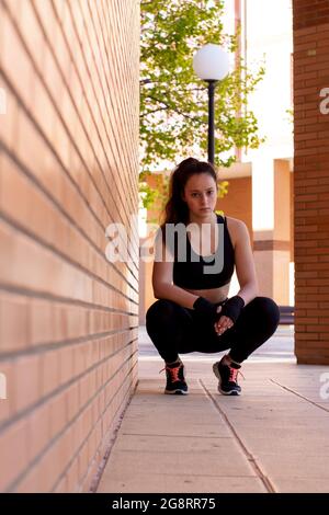 Giovane ragazza caucasica sportiva in posizione squatting dopo un duro allenamento Foto Stock