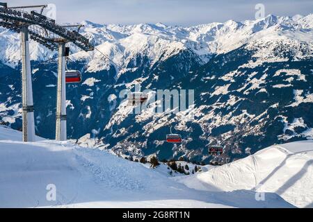 Seggiovia nelle Alpi sullo sfondo delle cime di montagna. Sciatori e snowboarder salgono sulla funivia. Stazione sciistica in Austria, Zillert Foto Stock