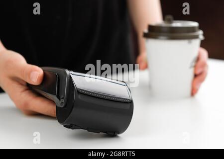 Donna dà il terminale POS per pagare un caffè in una caffetteria, Foto Stock