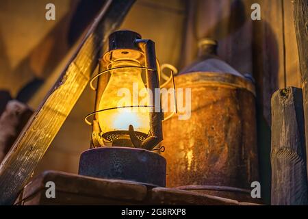 Fuoco selettivo su lampada da tempesta arrugginita illuminata e attrezzature d'epoca in fabbrica, officina o cantiere abbandonato a Belfast, Irlanda del Nord Foto Stock