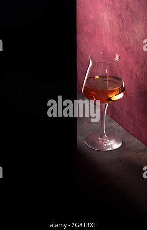 bicchiere di vino rosa su sfondo lilla concetto drammatico arte con ombre. Foto Stock