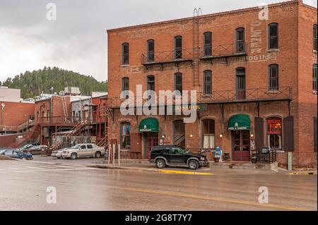 Deadwood, Stati Uniti d'America - 31 maggio 2008: Main Street centro. Hotel storico in mattoni rossi Bullock lato posteriore lungo l'autostrada CanAm sotto il cielo piovoso con auto parcheggiate Foto Stock