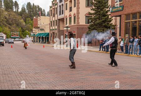 Deadwood, Stati Uniti d'America - 31 maggio 2008: Main Street centro. Shootout nel mezzo della strada. Vapore di polvere di pistola e onlooker. Edifici commerciali come backdro Foto Stock