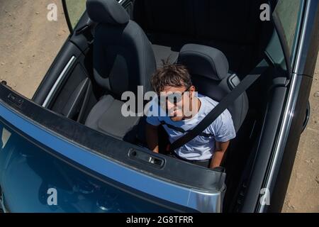 un ricco indiano seduto nella sua auto convertibile, foto dall'alto, sorridente ricco persona godendo la vita, uomo d'affari nella sua auto. Foto Stock