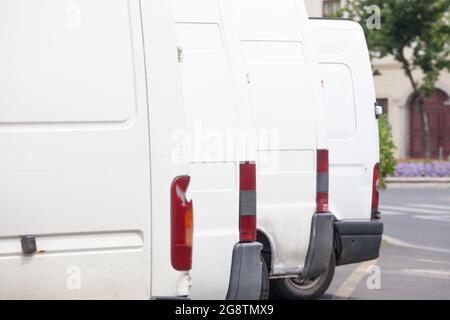 Immagine di camion di consegna bianchi, furgoni, parcheggiati in fila, in attesa di consegna pacchi e merci. Foto Stock