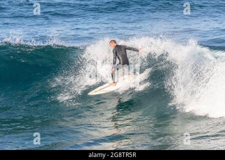 Surfista australiano maschile cavalcare le onde al largo della costa di Avalon Beach a Sydney in un giorno d'inverno, Australia Foto Stock