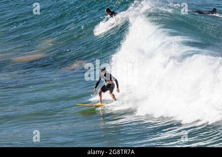 Surfista australiano maschile cavalcare le onde al largo della costa di Avalon Beach a Sydney in un giorno d'inverno, Australia Foto Stock