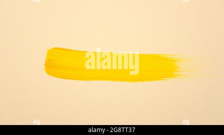 Pennello disegnato a mano tratto colore acrilico oro giallo brillante su sfondo tinta terra pastello. Texture artistica fluida su tela. Foto Stock