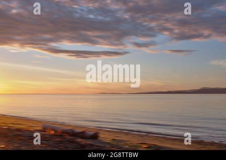 Il panning orizzontale (ICM) presso il campeggio del Parco Provinciale di Rathtrevor diffonde la luce dorata del tramonto sulla spiaggia, sul mare e sulle isole lontane. Vancouver è. Foto Stock