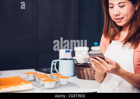 Donna proprietario panificio negozio utilizzando smartphone per la sua attività Foto Stock