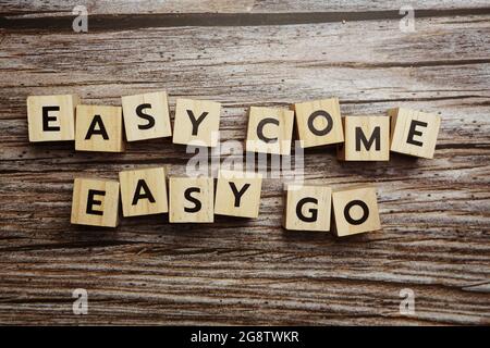 Lettere alfabetiche Easy come Easy Go su sfondo di legno; Foto Stock