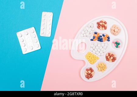Global Pharmaceutical Industry and Medicinal Products - Pillole, compresse e capsule di colore diverso su White Art palette con pill pacchetti giacenti su Split Blue e Pink sfondo, Flat Lay Foto Stock