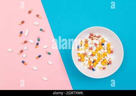 Global Pharmaceutical Industry and Medicinal Products - Pillole e capsule colorate in piatto bianco su sfondo blu e rosa Foto Stock