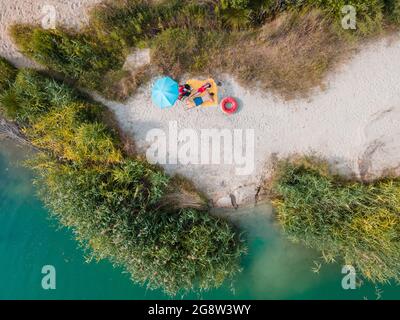 coppia che posa su coperta prendere il sole a spiaggia di sabbia blu azzurro acqua copia spazio estate Foto Stock