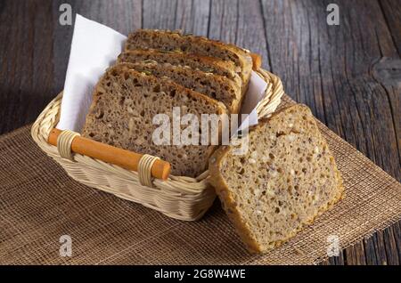 Fette di pane con semi diversi in cestello su tavolo di legno scuro Foto Stock