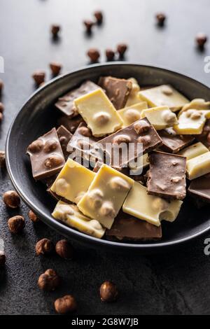Cioccolato bianco noci e scuro con nocciole sul piatto. Foto Stock