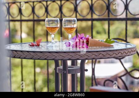 Cocktail estivi luminosi con fiori rosa di bougainvillea su un tavolo di vetro. Concetto di rinfresco. Estate fiori surreali luminosi e bevande fatte in casa. COP Foto Stock