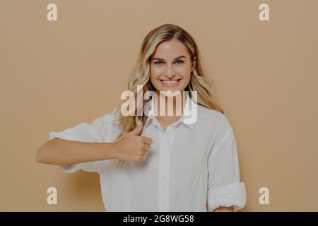 Ritratto di giovane donna positiva con ampio sorriso che mostra il pollice in su gesto con la mano Foto Stock