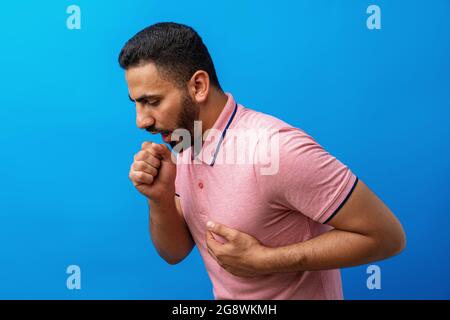Giovane arabo che si sente malato e tosse su sfondo blu Foto Stock