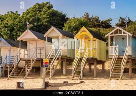 29 giugno 2019: Wells-Next-the-Sea, Norfolk, Inghilterra, UK - Bathing huts sulla spiaggia, alberi dietro. Foto Stock