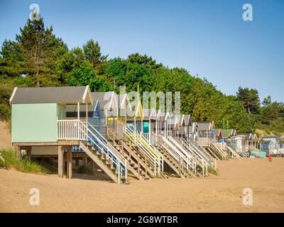 29 giugno 2019: Wells-Next-the-Sea, Norfolk, Inghilterra, UK - Bathing huts sulla spiaggia, alberi dietro. Foto Stock