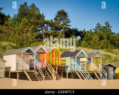 29 giugno 2019: Wells-Next-the-Sea, Norfolk, Inghilterra, UK - Bathing huts sulla spiaggia, alberi dietro. Foto Stock