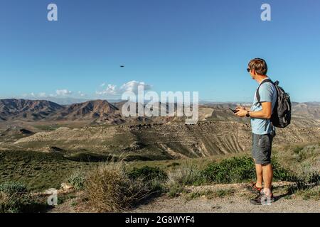 Uomo che gioca con il drone per l'esame. Silhouette contro paesaggio di montagna.Male funzionamento del drone da telecomando e divertirsi. Drone pilota volante. Foto Stock