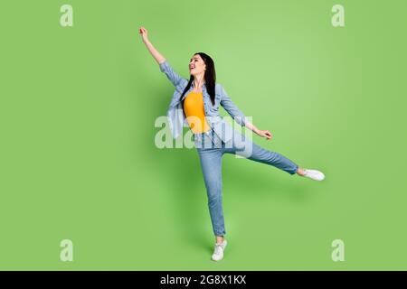 Profilo a dimensione intera foto laterale di giovane affascinante donna sorridente tenere l'ombrello invisibile isolato su sfondo di colore verde Foto Stock