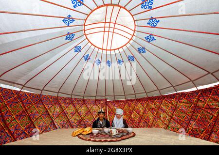 Coppia kirghiza in abiti locali, in una tenda nomade conosciuta come yurt, vicino Bishkek, Kirghizistan. Foto Stock