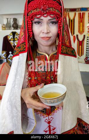 Donna uzbeka in abito da sposa tradizionale che offre tè a Nukus, Uzbekistan Foto Stock