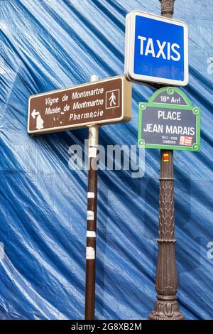 Vari cartelli di fronte a un telone blu su Place Jean Marais a Montmartre, Parigi Foto Stock