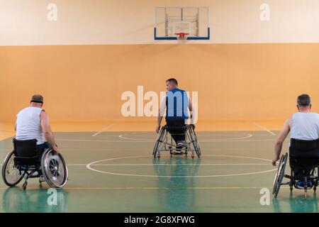 I veterani della guerra disabili hanno giocato una gara mista contro squadre di pallacanestro in carrozzina fotografate in azione mentre giocavano una partita importante in una sala moderna. Foto Stock