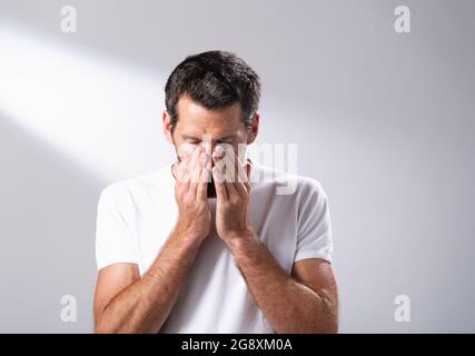 L'uomo che usa un olio per il viso per massaggiare la sua pelle. Foto Stock