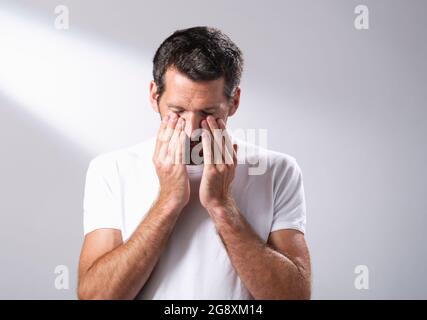 L'uomo che usa un olio per il viso per massaggiare la sua pelle. Foto Stock