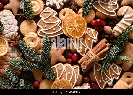 Modello di biscotti glassati di Natale forme diverse, cannella, stelle di anice, bacche rosse, patatine d'arancia, rami di abete rosso. Festivo sfondo panetteria. Vi Foto Stock