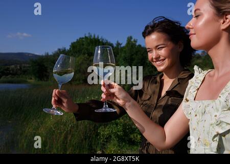 due giovani donne che tengono bicchieri di vino. Foto Stock