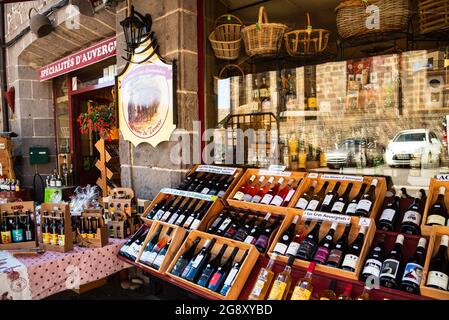 Besse, Francia - 30 maggio 2021: All'aperto di cibo locale e negozio di specialità del vino nella città medievale in Auvergne. Strada riflessa nella finestra di visualizzazione. Foto Stock