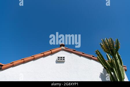 facciata laterale di casa con tetto e cactus. edificio residenziale con nessuno, architettura concetto. tetto di abitazione su sfondo blu cielo. Foto Stock