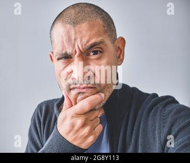 Uomo di mezza età con la mano sulla domanda di pensiero del mento, espressione pensiva. Sorridendo con il volto pensieroso. Concetto di dubbio. Isolato sulla parete bianca dello studio. Foto Stock