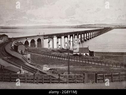 Una vista del tardo 19 ° secolo del ponte Tay che porta la ferrovia attraverso il Firth of Tay in Scozia tra Dundee e il sobborgo di Wormit a Fife. La sua estensione è di 2.75 km (4.43 miglia). I piani per un ponte sul Tay per sostituire il servizio di traghetto ferroviario sono emersi nel 1854, ma il primo Tay Bridge non è stato aperto fino al 1878. Il ponte crollò improvvisamente in venti forti l'anno seguente. Fu sostituito dal secondo ponte (nella foto) costruito in ferro e acciaio con una doppia pista parallela ai resti del primo ponte. I lavori iniziarono nel 1883 e il ponte fu aperto nel 1887. Foto Stock